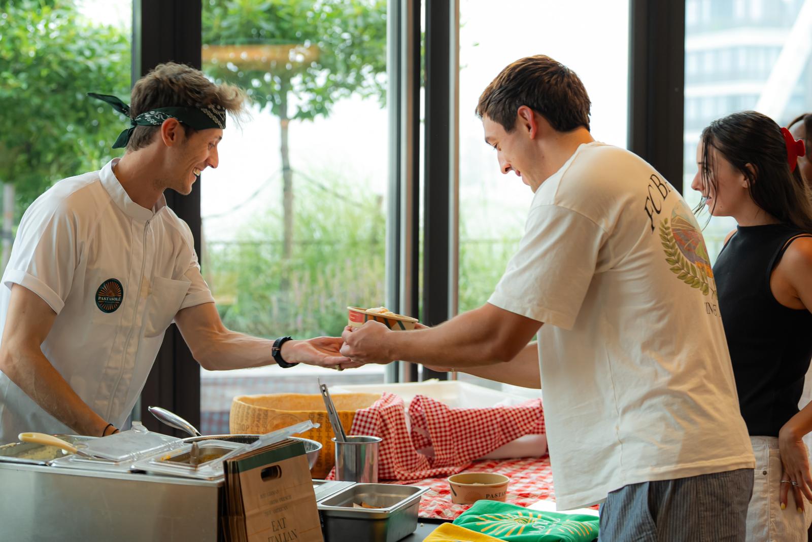 Pastasole chef handing a bowl of pasta to a smiling guest