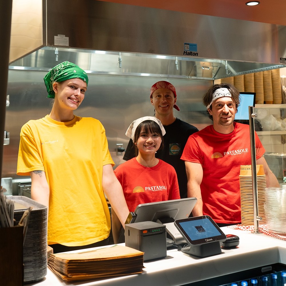Smiling Pastasole team behind the counter in branded shirts and bandanas