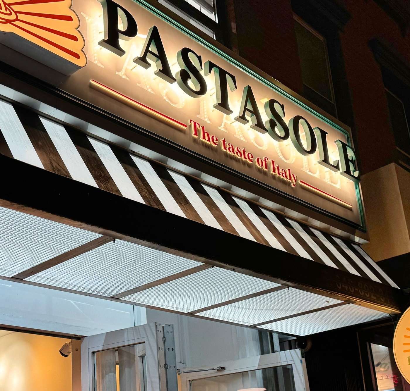 Illuminated Pastasole storefront sign at night in the East Village, New York