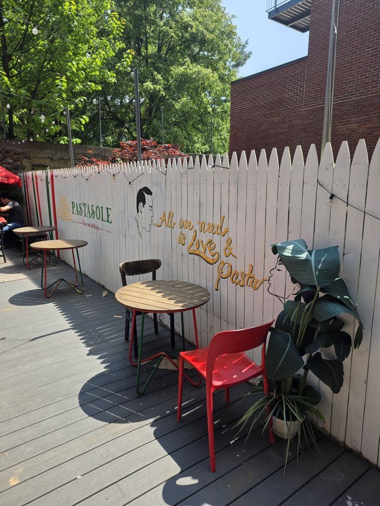 Backyard patio at Pastasole East Village with tables and a hand-painted Love & Pasta mural